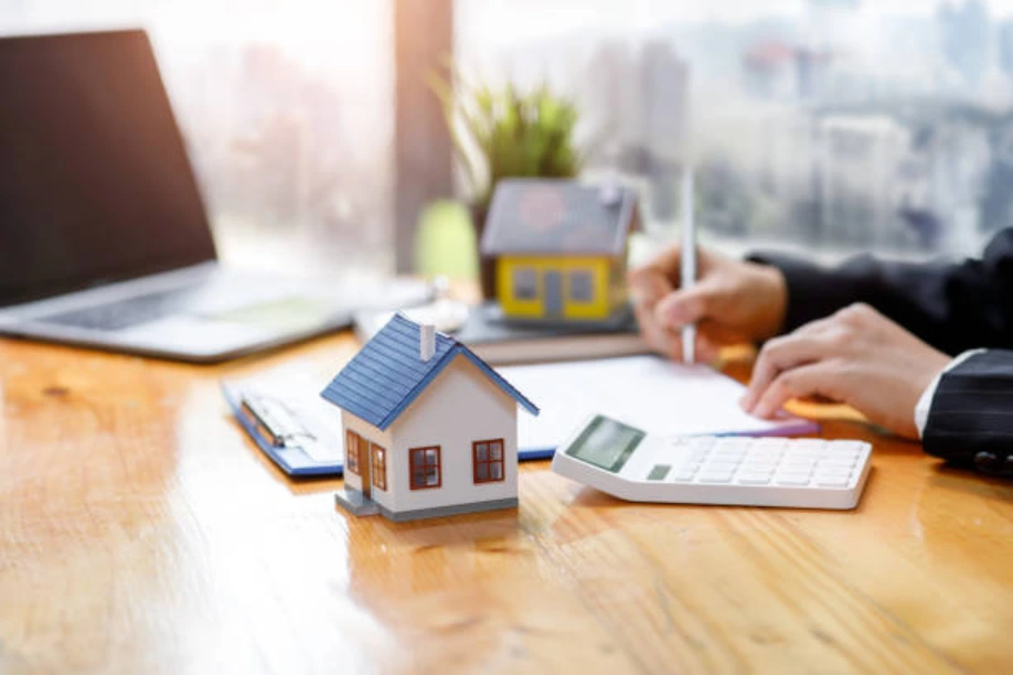 Small house model beside a calculator and paperwork during a buy-to-let mortgage affordability review